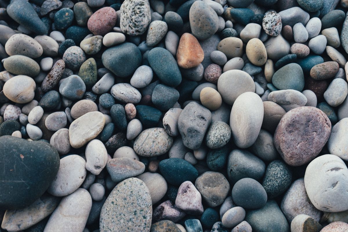 Overhead view of smooth water-worn pebbles in grey, blue, tan, and reddish-brown shades